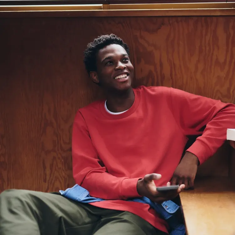Adult model in a red sweatshirt with a blue shirt tied at the waist, from the UNIQLO autumn collection