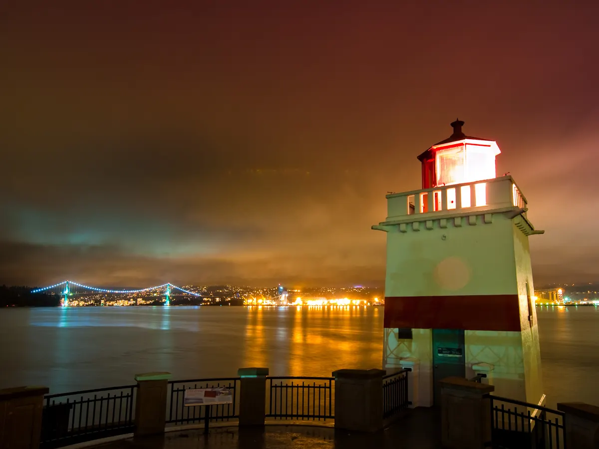 Brockton Point Lighthouse at night with the lit Lions Gate Bridge behind