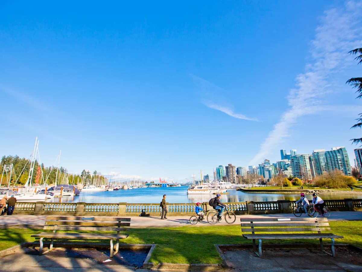 The Stanley Park seawall along Coal Harbour, with benches, cyclists and the downtown skyline
