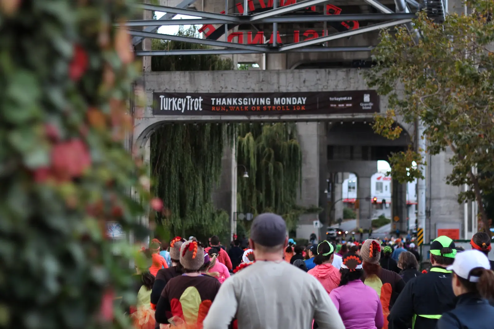 Runners gather beneath a Turkey Trot Thanksgiving Monday banner in a covered passage at Granville Island