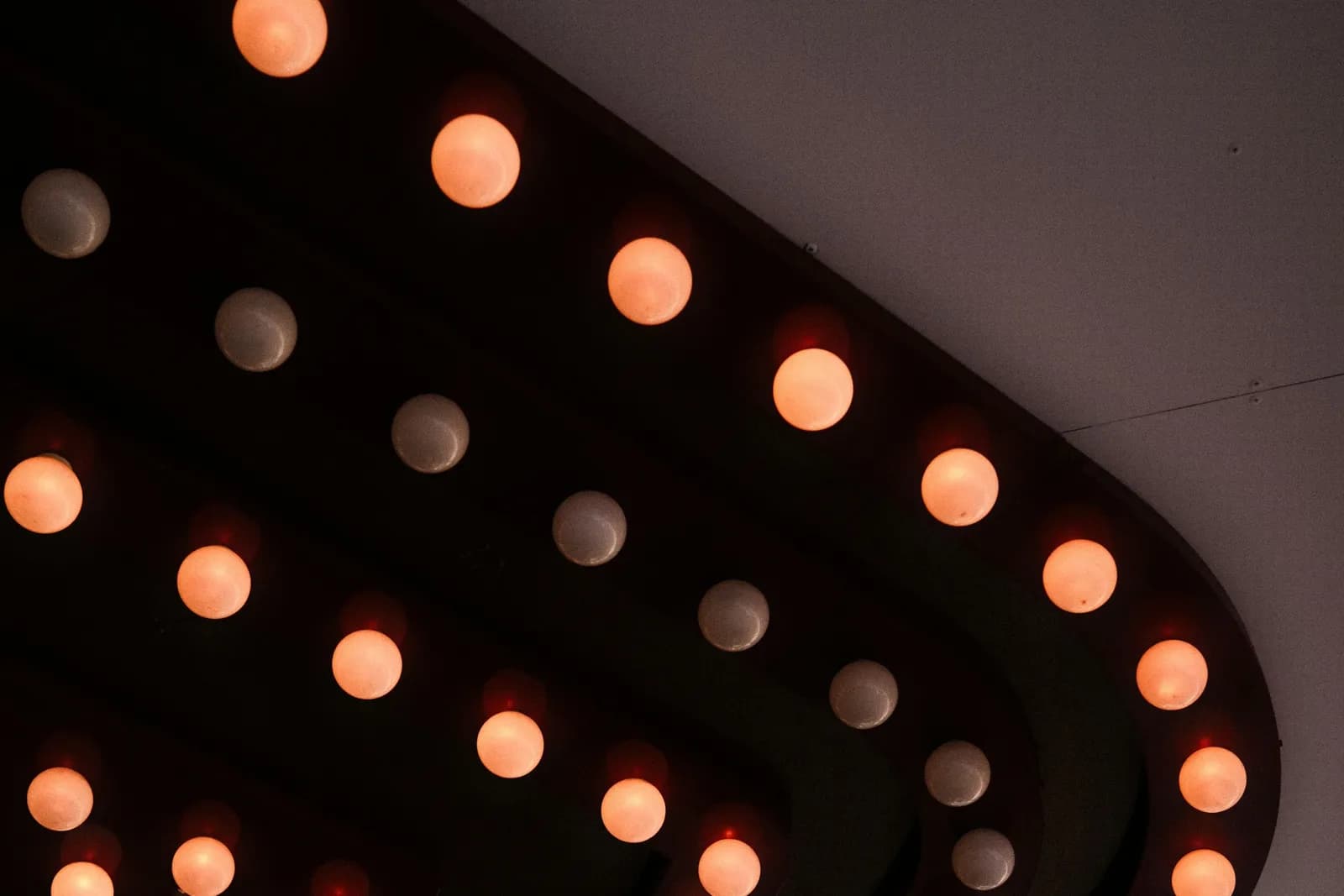 Rows of glowing orange marquee light bulbs on a dark cinema canopy, a stock photo used to illustrate the Rio Theatre's Rocky Horror screenings