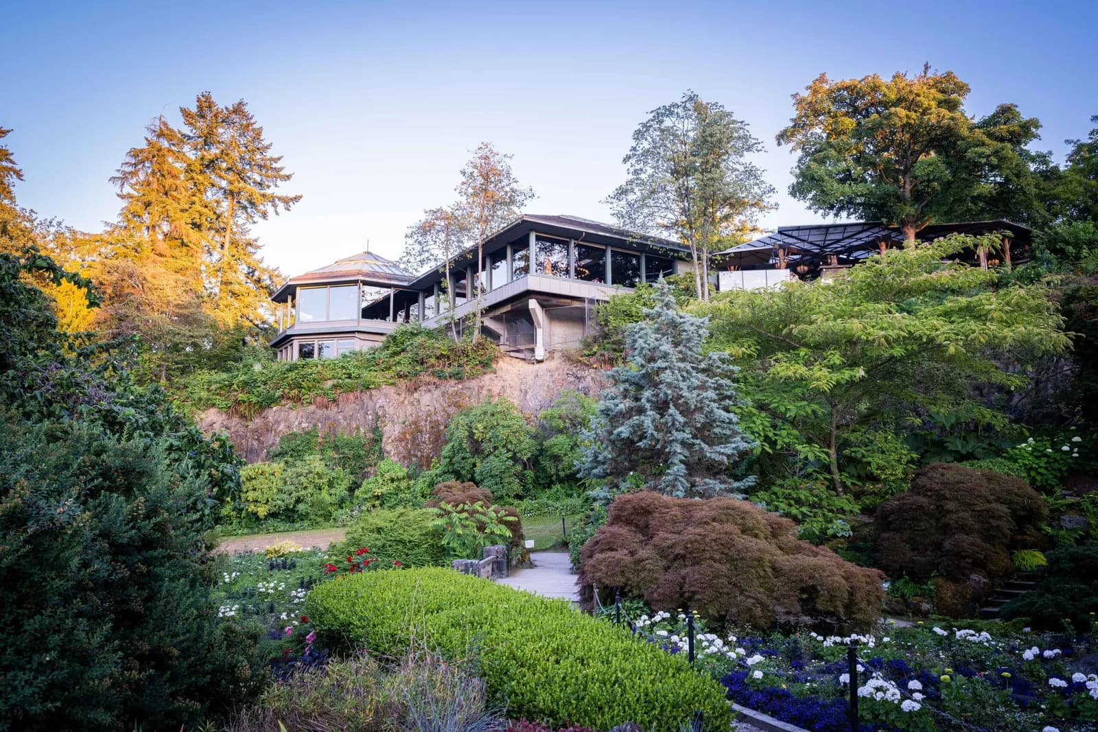Seasons in the Park restaurant at golden hour, its glass-walled dining rooms on the hilltop above the flower gardens of Queen Elizabeth Park