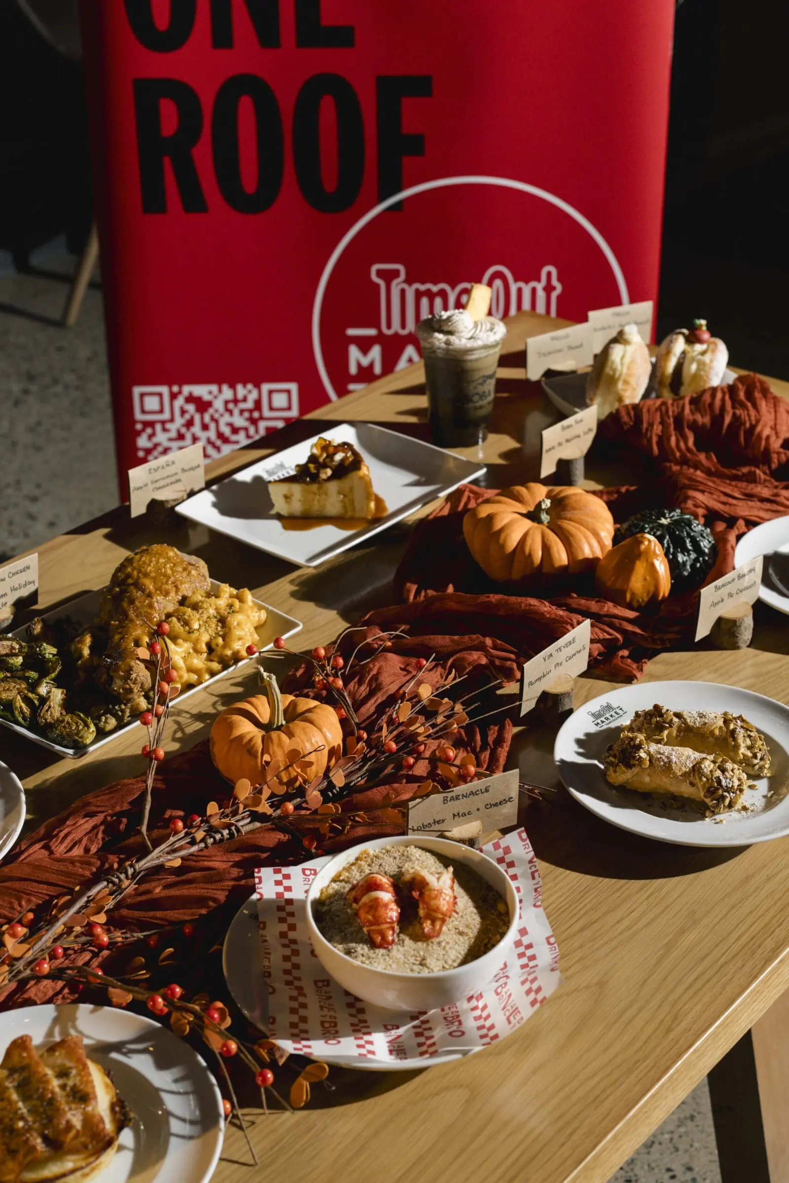 A table spread with assorted Thanksgiving dishes and pastries, with a red Time Out Market sign visible in the background