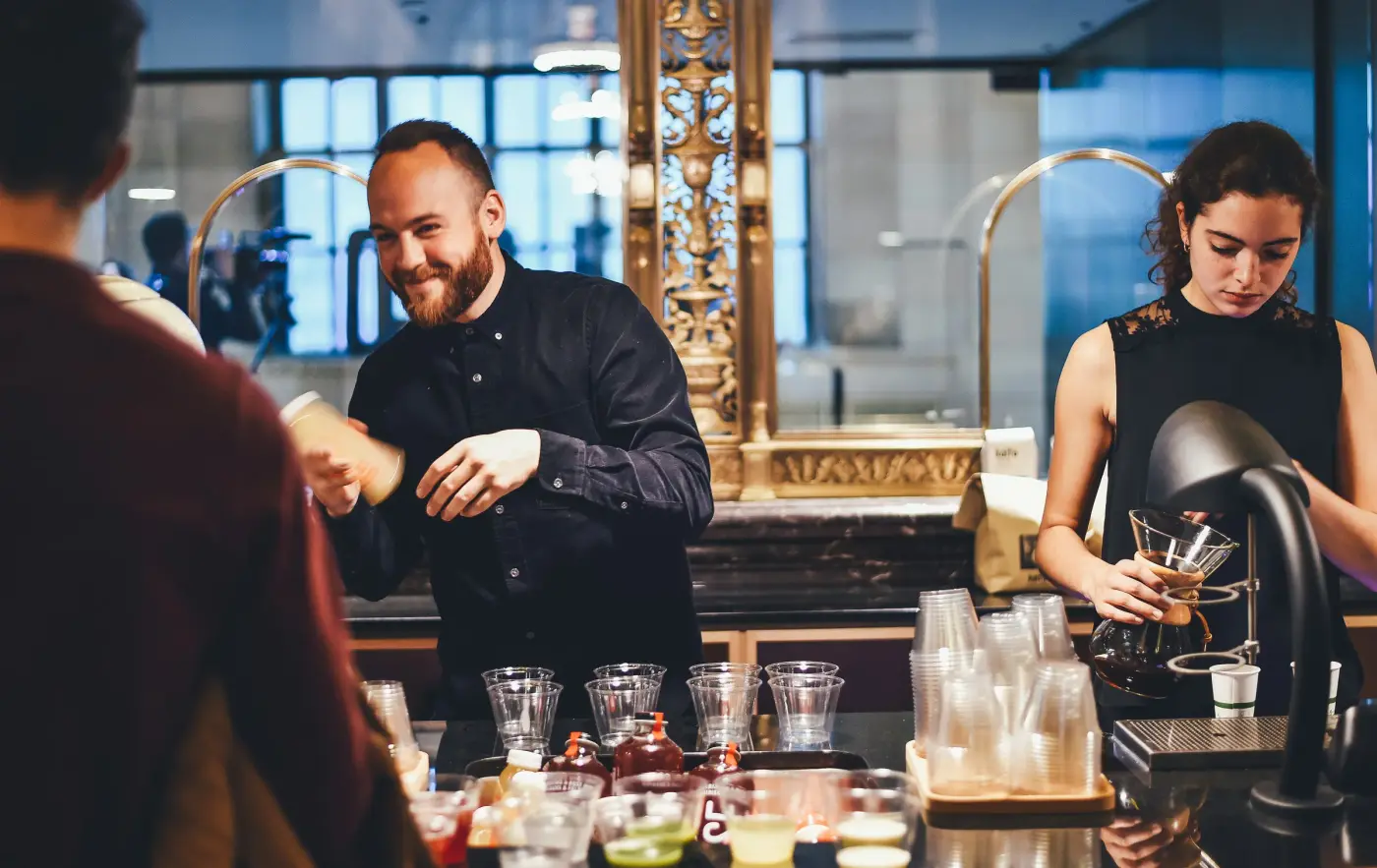 Bartenders serving cocktails at a busy bar