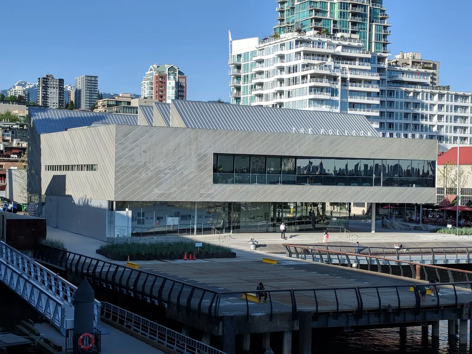 Exterior of the Polygon Gallery in North Vancouver, viewed from Lonsdale Quay, with the waterfront boardwalk and residential towers behind it