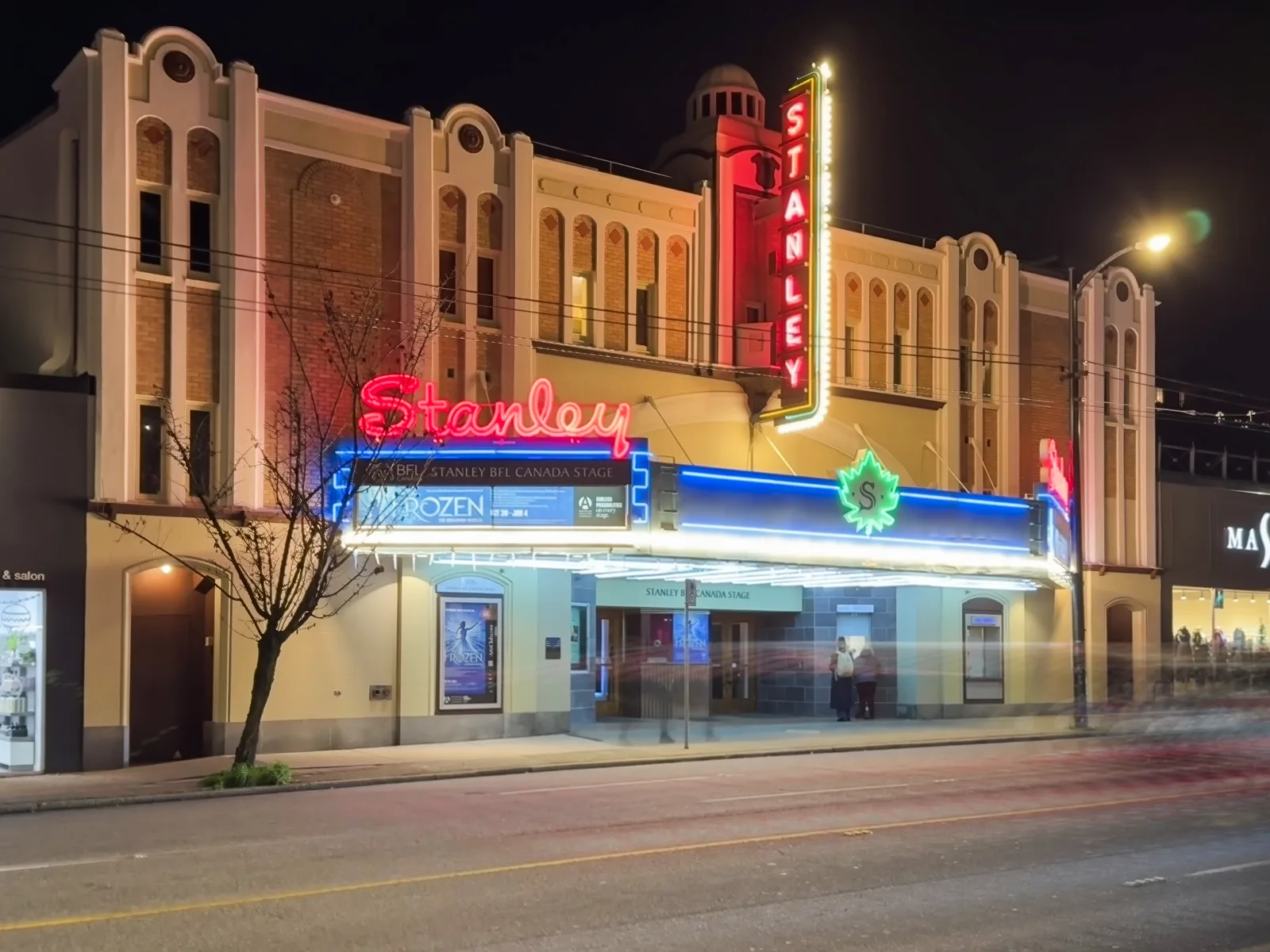 The Stanley Theatre on Granville Street at night, its neon Stanley signs lit and the marquee advertising an earlier production