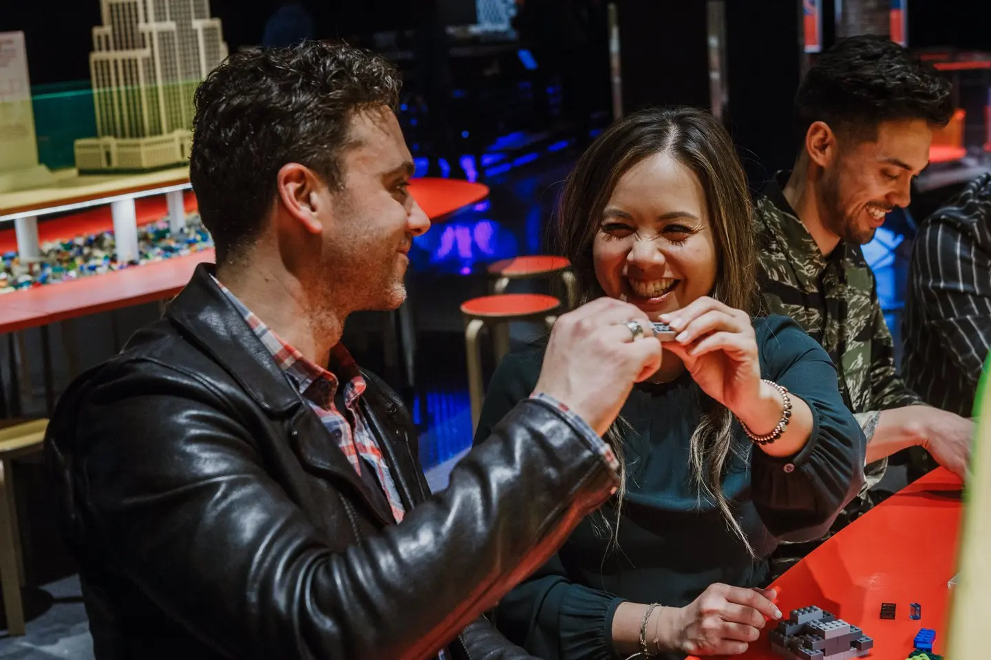 Adults enjoying interactive exhibits and drinks at Science World After Dark, with illuminated displays and gallery installations visible in the background