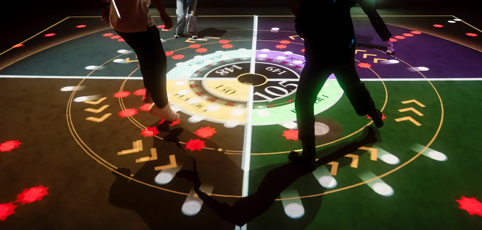 Players' legs and shadows on the glowing projected court of the Target game, cropped from a photo on Wonderground's booking page